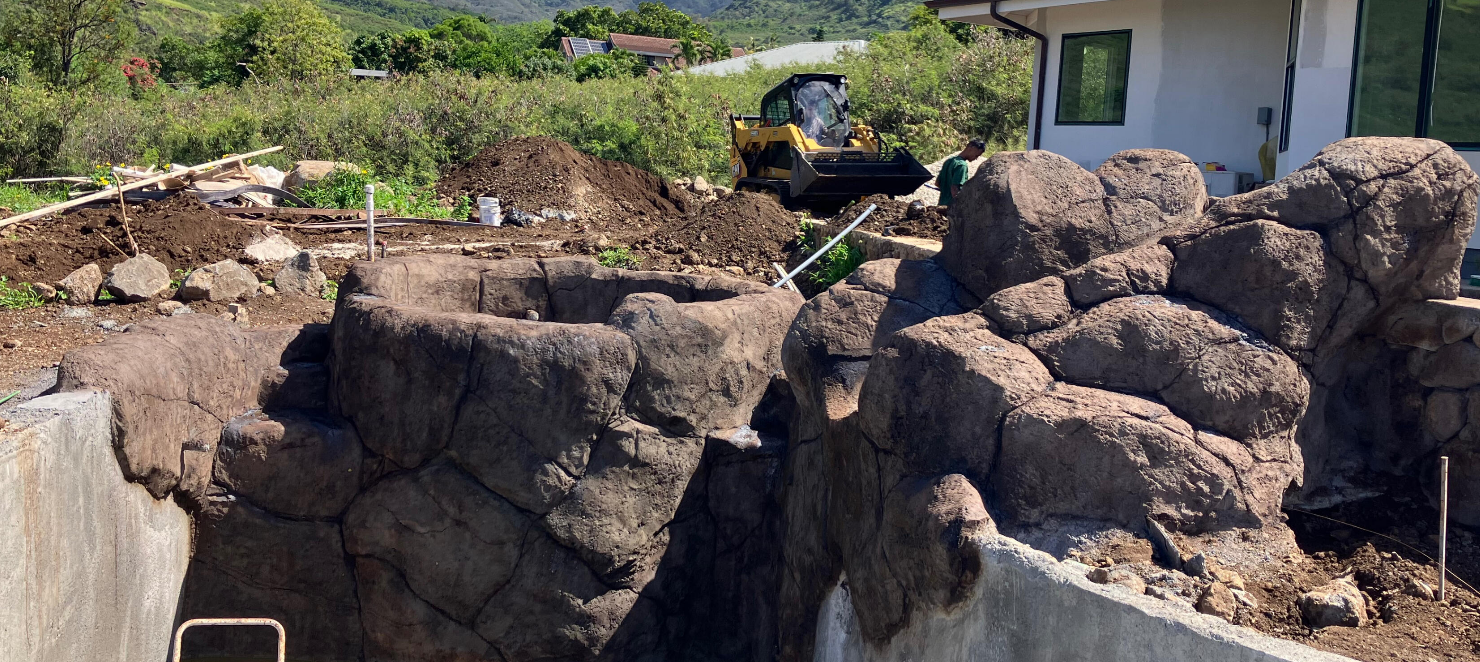 Sculpted rockwork and boulders around a pool during construction