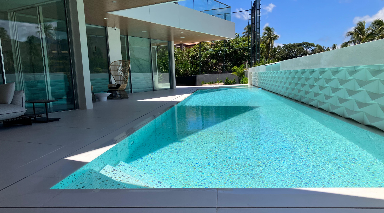 Finished blue-tiled swimming pool beside a modern Hawaii home